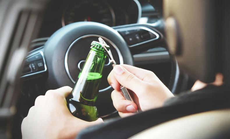 A man opens a bottle of beer behind the wheel