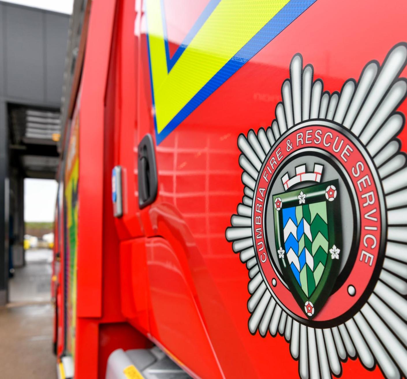 An image of the yard at Carlisle East Fire Station, with a close up on a red fire engine door, showing the Cumbria Fire and Rescue Service logo