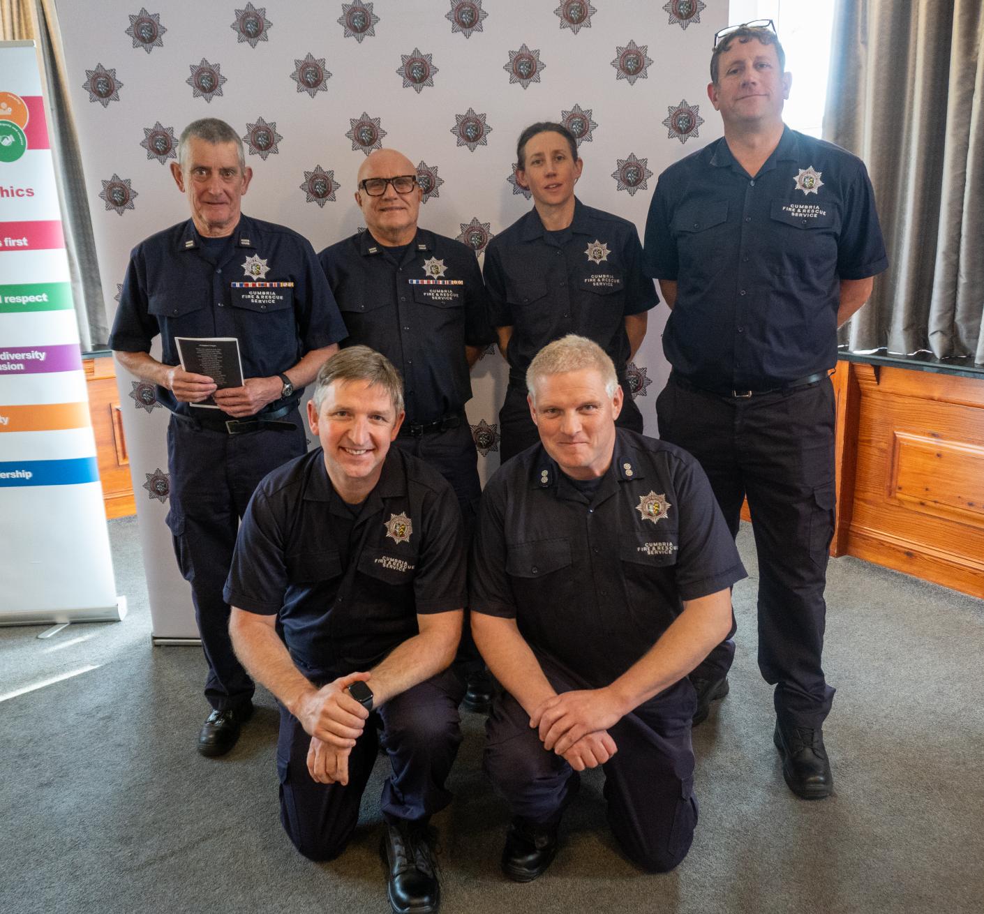 A team of firefighters pose for a photograph at an awards ceremony