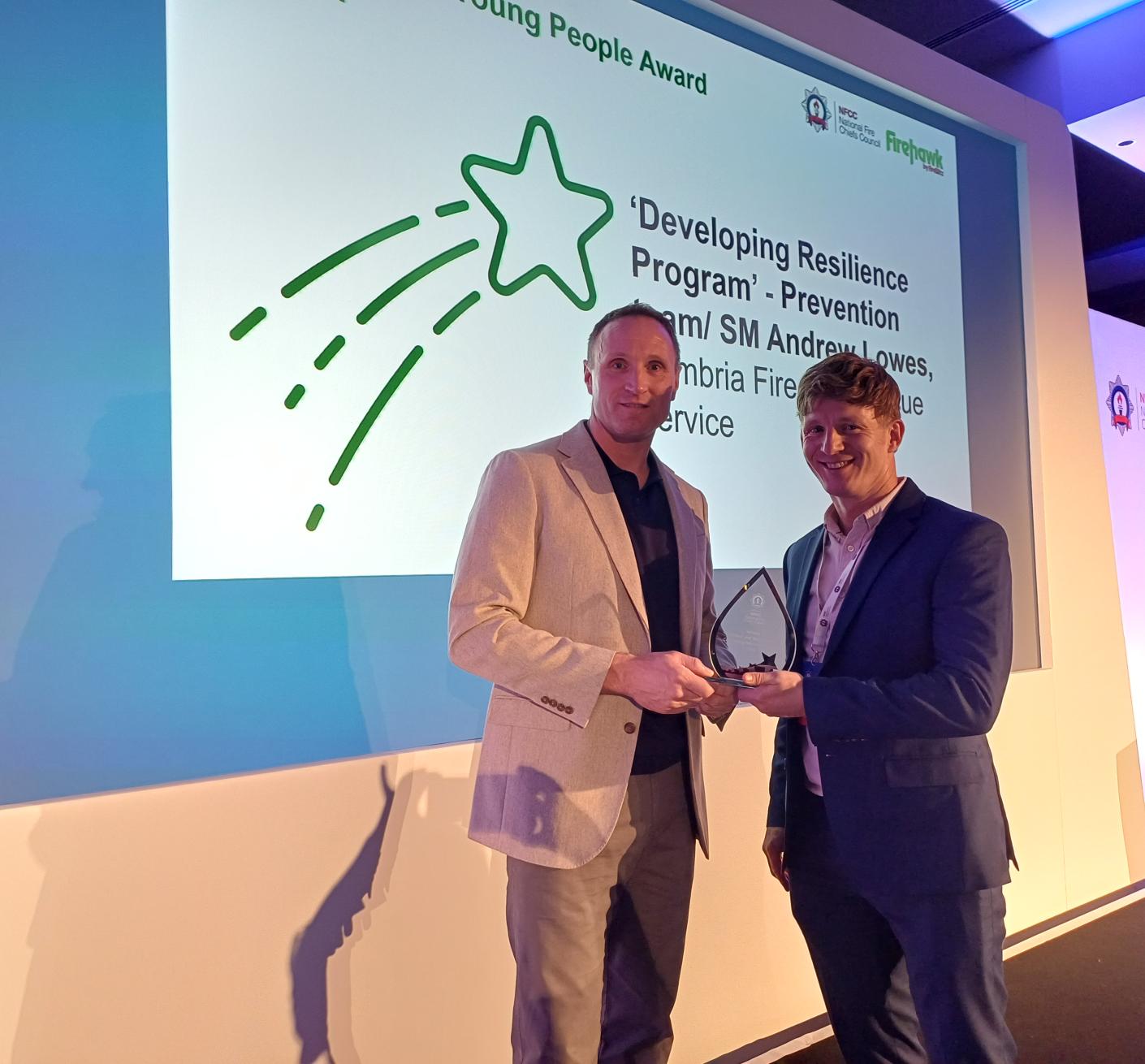 A firefighter is presented an award on stage