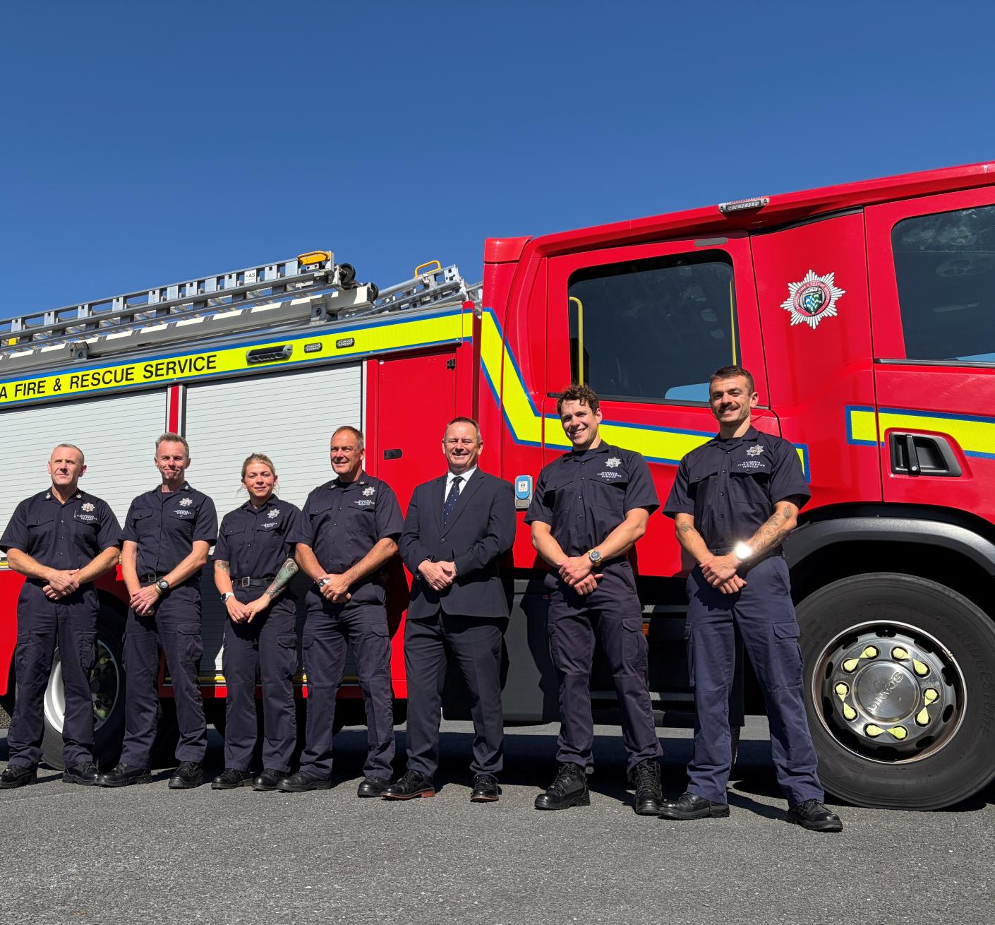 A group of people stand side by side in front of a fire engine
