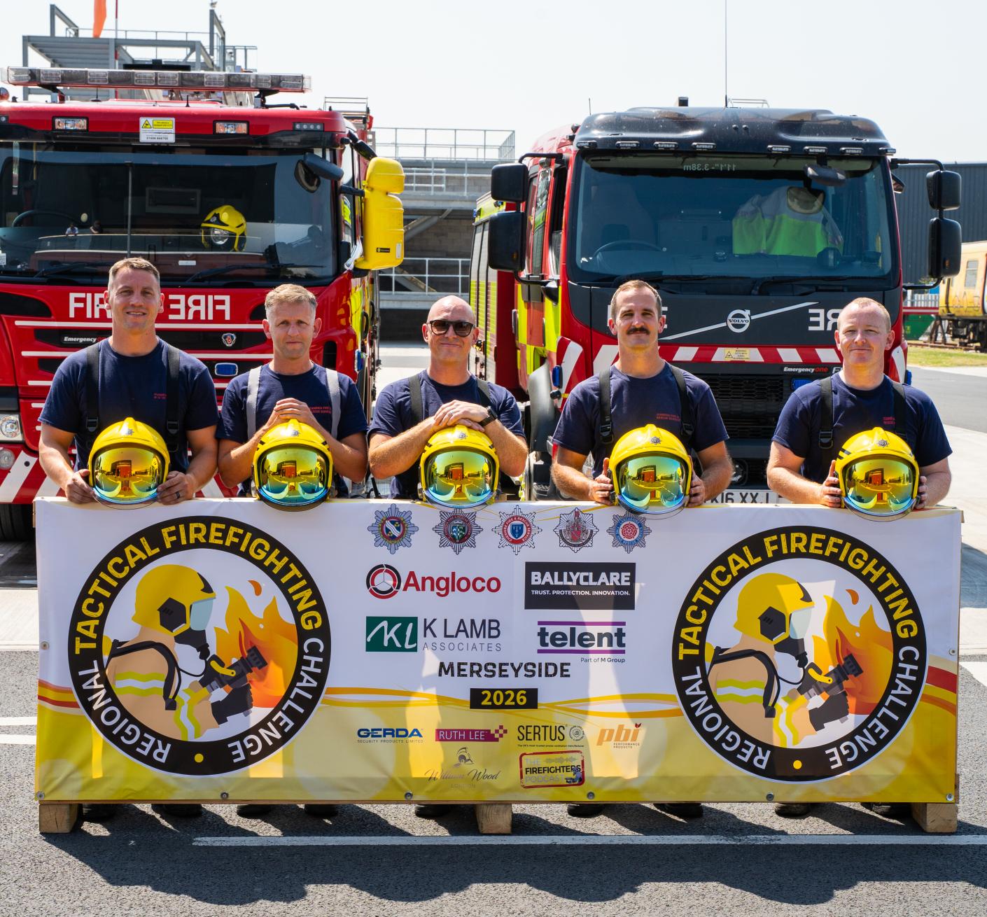 Five firefighters pose with their helmets in front of three fire engines