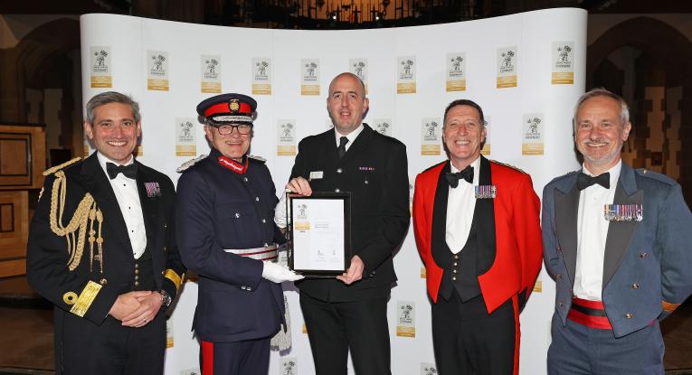 A firefighter is presented an award, flanked by dignitaries