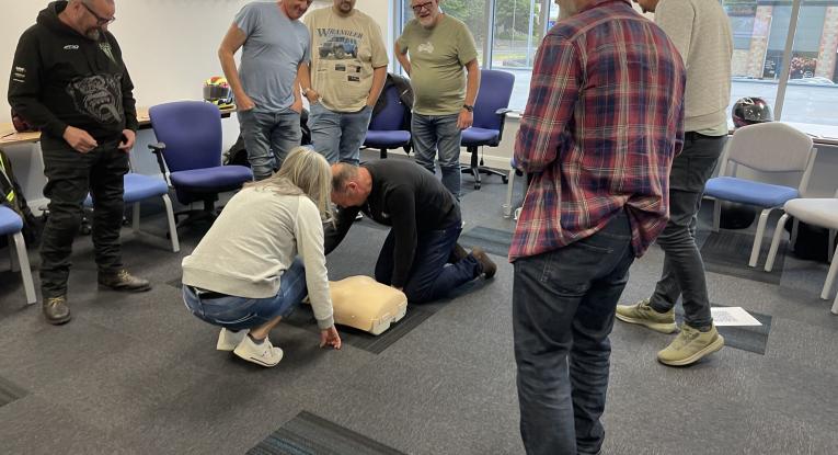 A man and woman crouch over a dummy