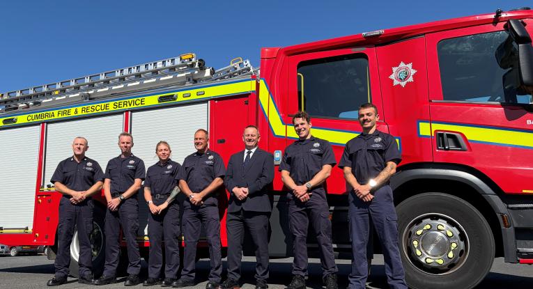 A group of people stand side by side in front of a fire engine